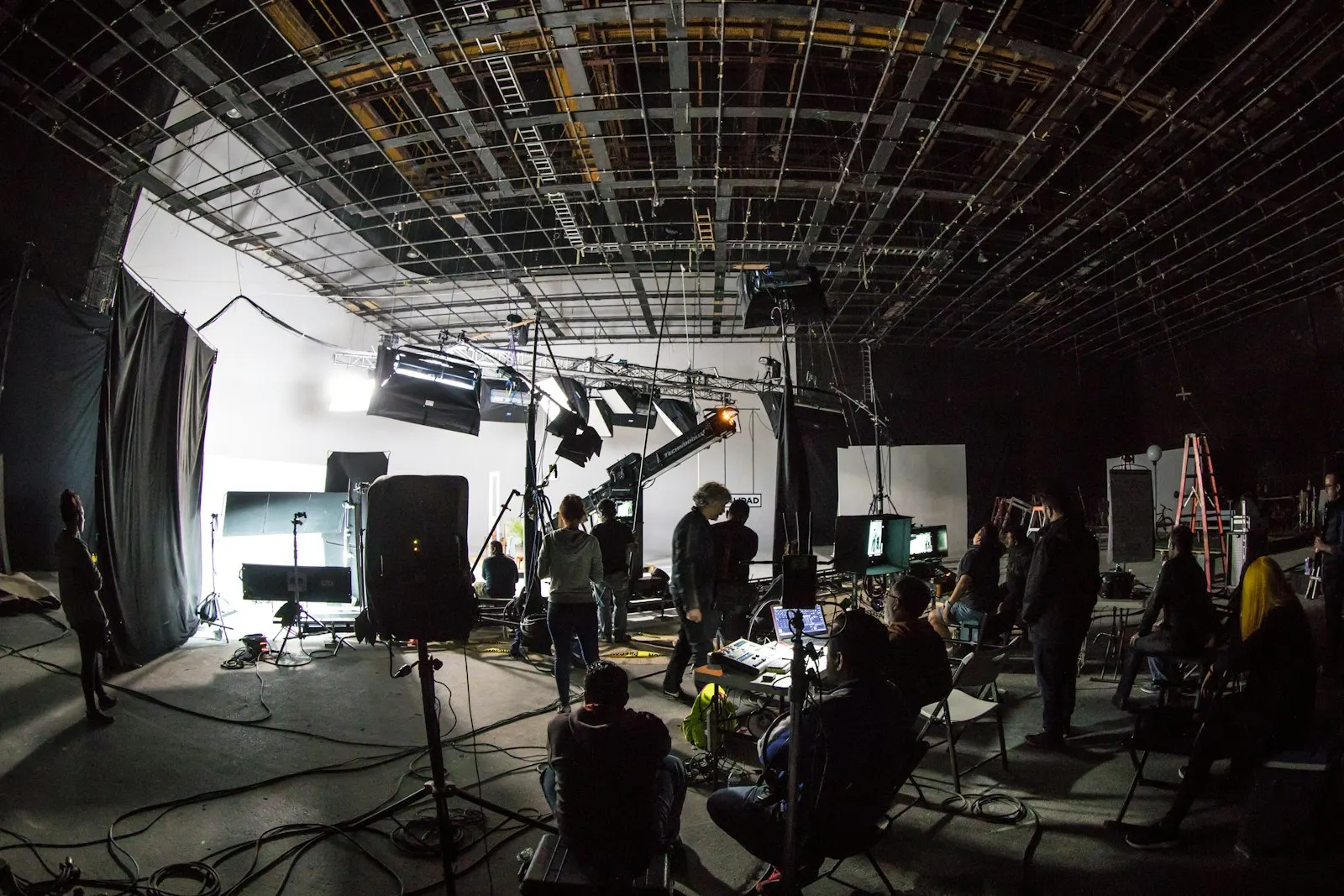 Film crew working on a dark soundstage with lighting rigs and monitors